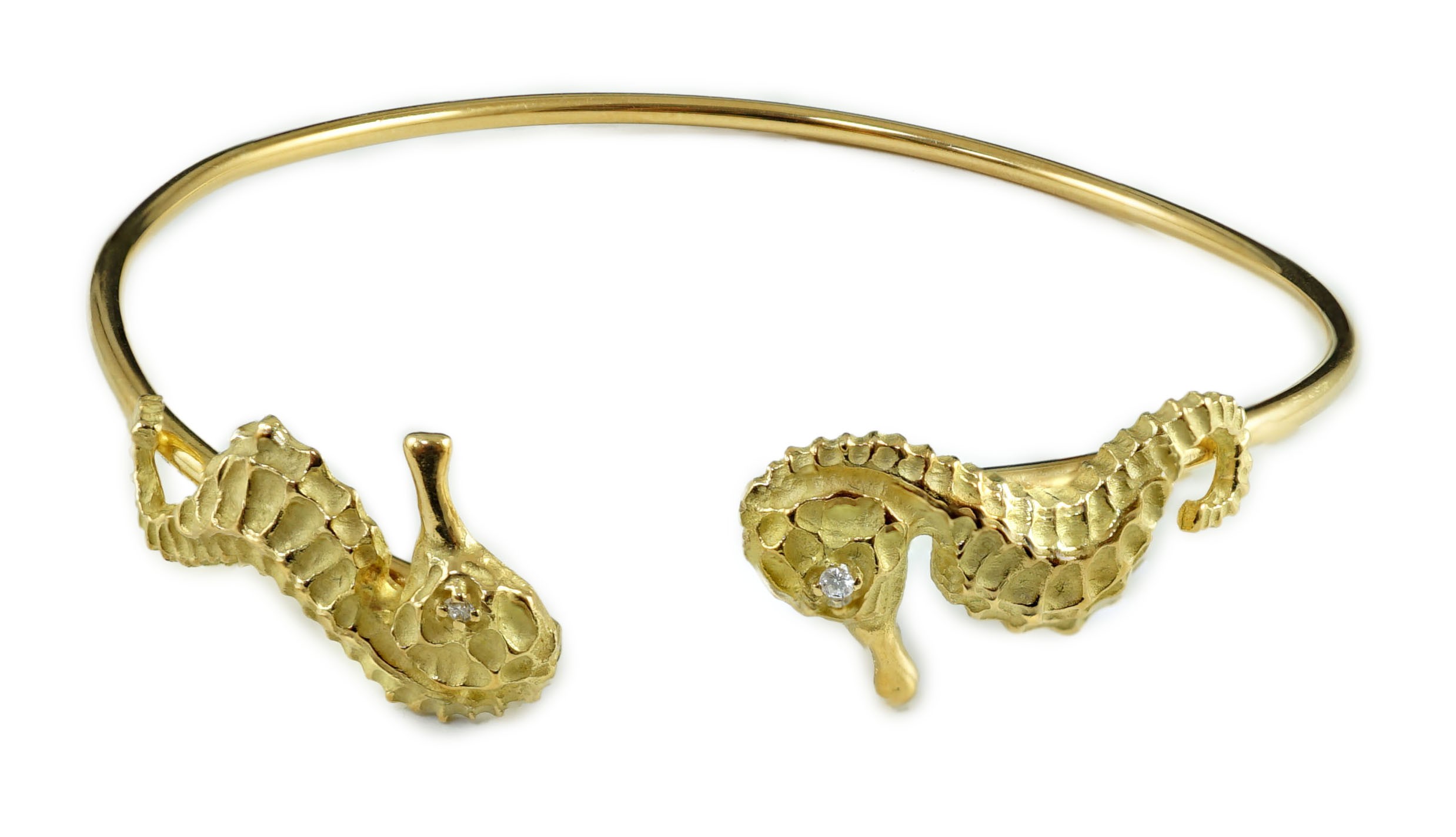 A modern gold and diamond chip set open work bangle, each terminal modelled as a seahorse with diamond chip eye